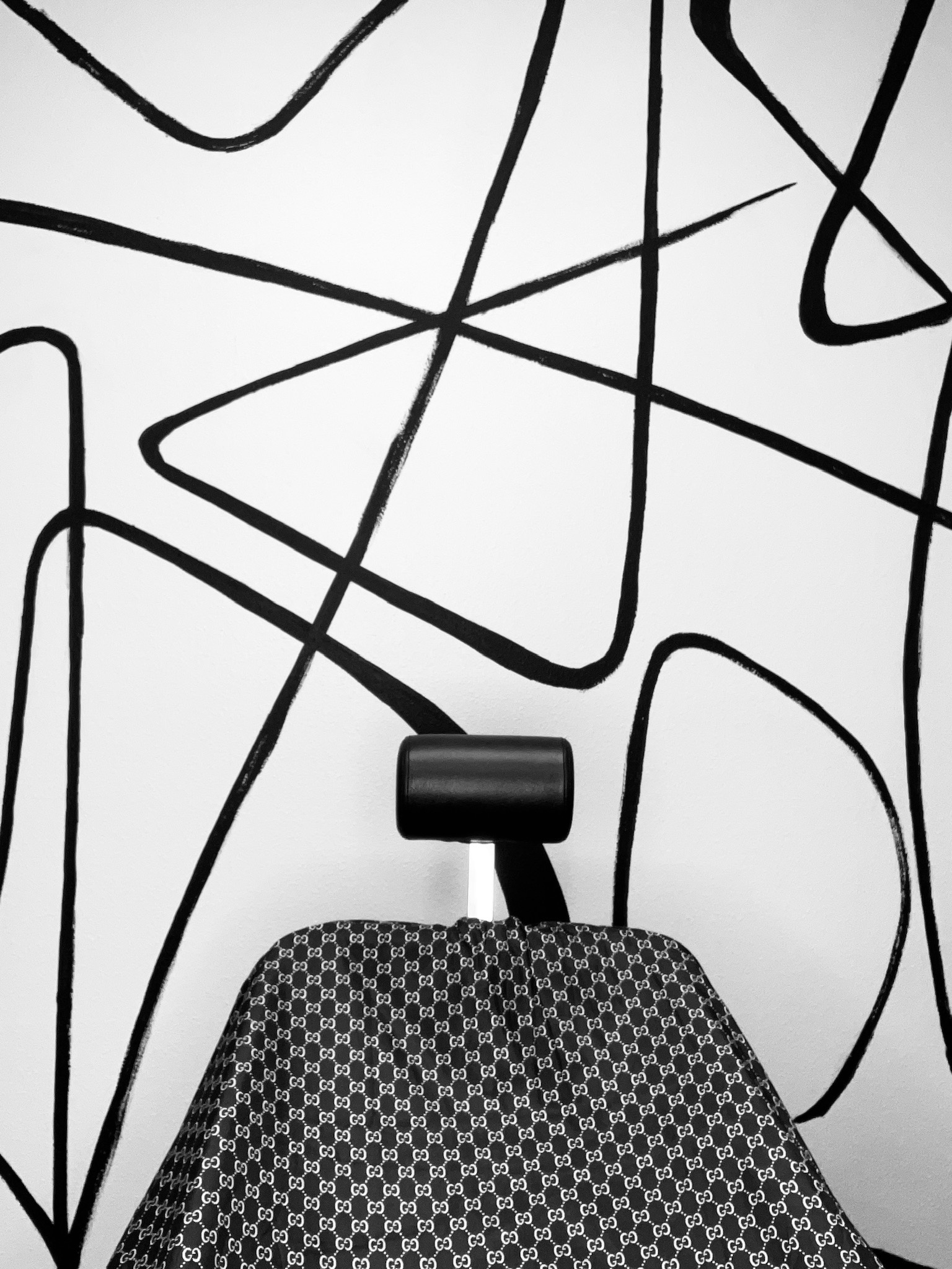 A barber chair draped in a patterned cape against a bold black-and-white mural.